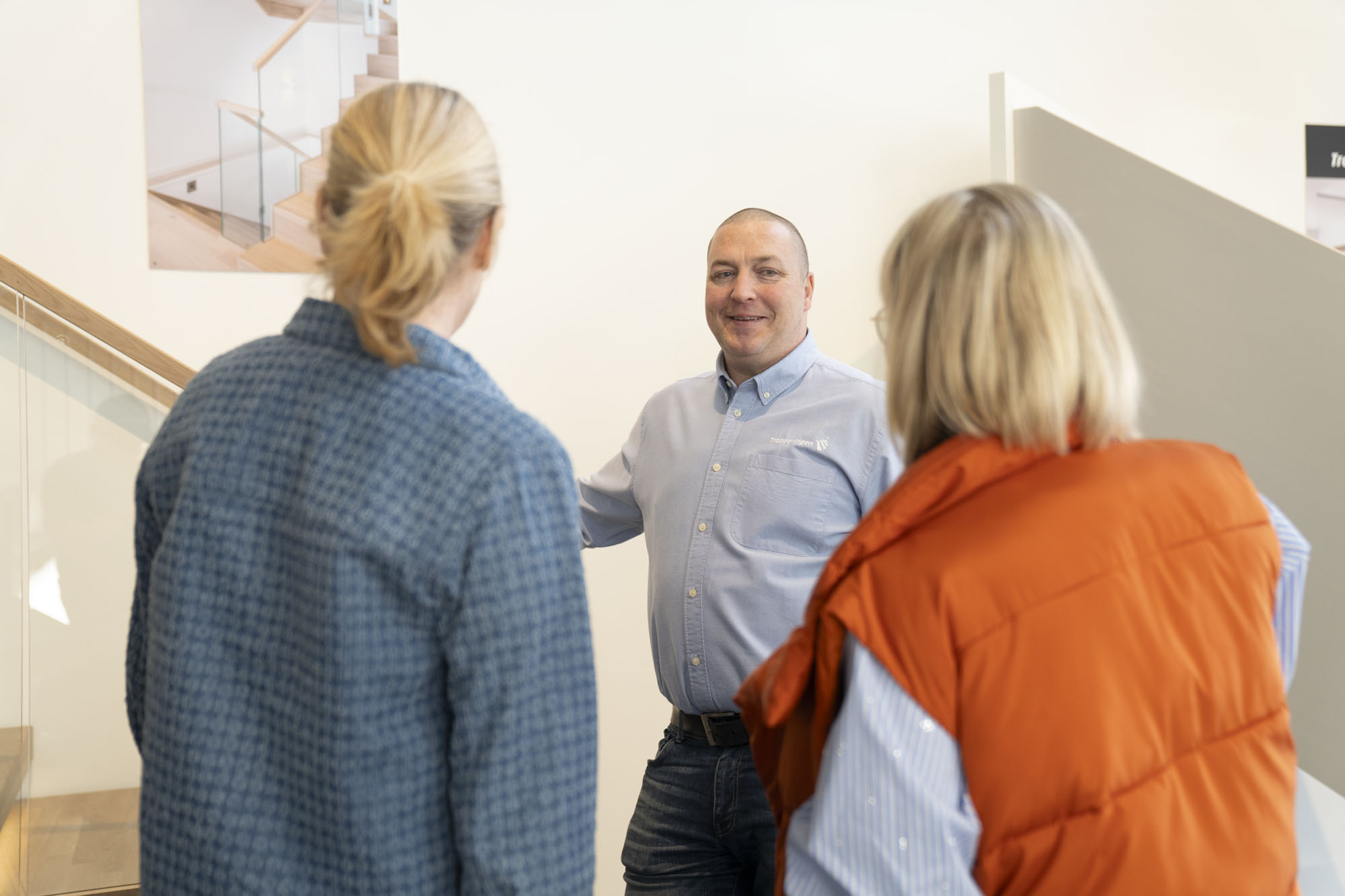 Trappemaker i samtale med to kunder i et trappestudio